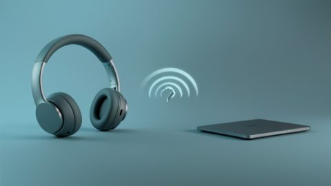 Conceptual illustration of wireless headphones beside a laptop with a broken sound-wave link between them, evoking a Bluetooth device that pairs but plays no audio