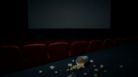 Conceptual illustration of empty cinema seats in a dark theater with a spilled drink cup on the floor, evoking a disrupted screening